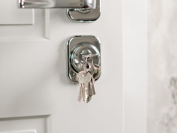 A key with a tag sitting in the lock of a white panelled front door