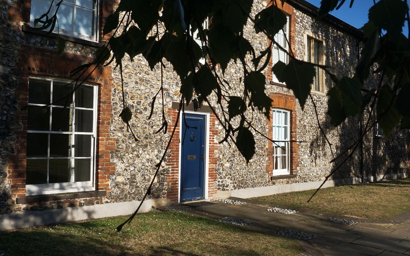 An old flint walled house in Norwich with a blue front door and sash windows