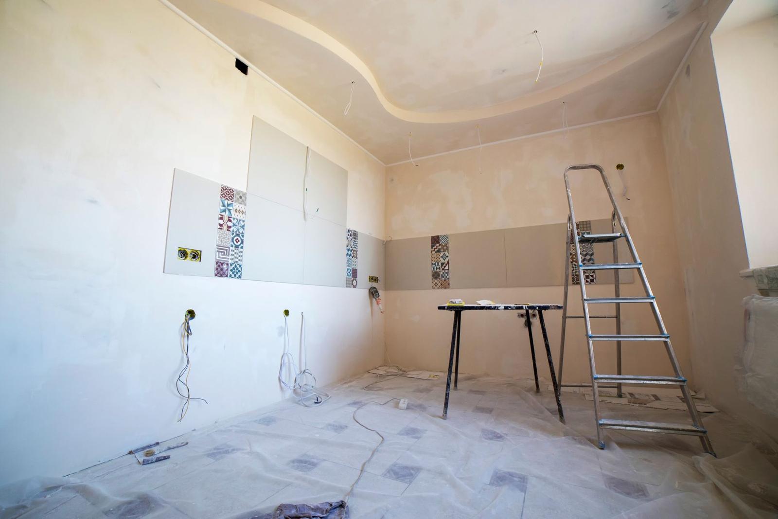 An empty room part way through refurbishment, with freshly plastered walls, a stepladder and a trestle table
